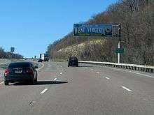 A sign above the highway reads "Welcome to West Virginia—Open For Business." An adjacent sign reads "Preston County."