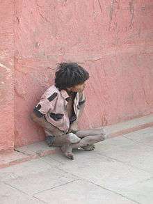 a poor boy sitting in the streets of mumbai