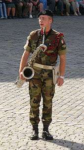 A military band saxophonist holding baritone saxophone