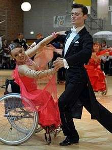 A wheelchair-bound woman in a ball gown dances with a man in a tuxedo