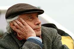 Older man, warmly dressed, resting his cheek on his hand