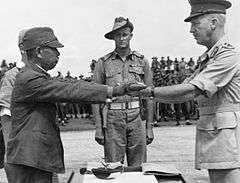 A Japanese officer hands his sword to an Australian during a surrender ceremony