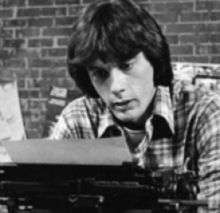 man bent over a typewriter reading
