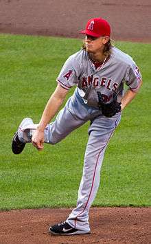 Jered Weaver, wearing a red baseball cap and grey baseball uniform with the words ANGELS across and an "A" patch on the right sleeve, delivers a pitch