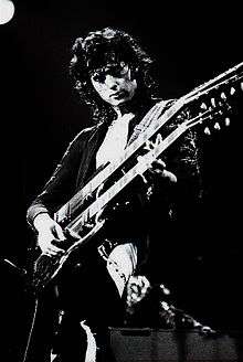 A black and white photograph of Jimmy Page playing a double-necked guitar