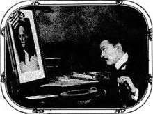 Barrymore sitting at a desk in profile, looking at a picture of George Washington