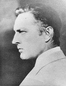 A cleanshaven Barrymore, seen from behind, over his left shoulder, glaring to his left