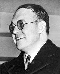 Smiling man in round-rimmed glasses