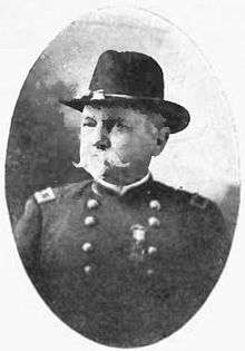 Head and shoulders of a white man with a Van Dyke beard and mustache wearing a military uniform with a cavalry hat.