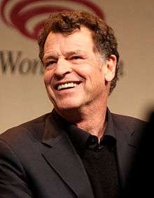 A 63-year old, dark-haired man, smiling at the left of the camera.