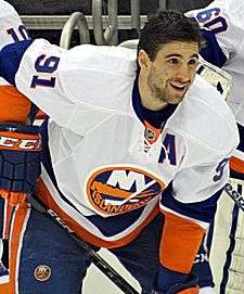 John Tavares in a white away New York Islanders jersey leaning forward and holding his hockey stick