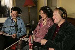 Steven Moffat, Fiona Gillies and Robert Bathurst sitting in a recording studio behind a row of microphones