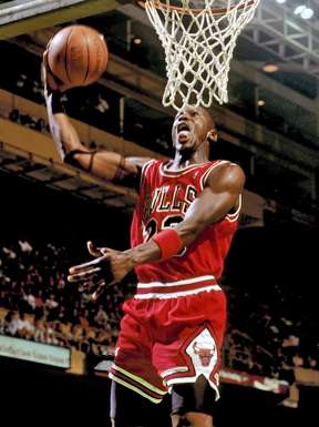 A basketball player wearing a red jersey while in the air.
