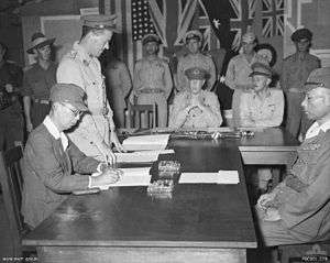 Two Japanese officers sitting at a desk during a surrender ceremony
