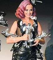 A picture of a woman with pink hair holding awards
