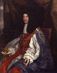 Seated man of thin build with chest-length curly black hair