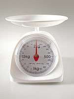 A kitchen scale with one scalepans and a dial to indicate the weight