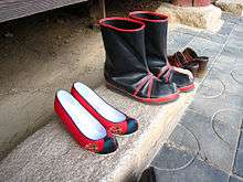 A pair of low, red women's shoes and a pair of black boots on a step