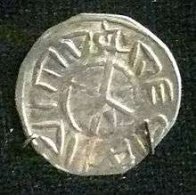 A small silver coin depicting a cross