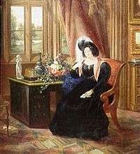 A color picture of an 1833 painting of Lady Tyrconnell sitting in a brown covered chair wearing an 1830s dark blue full dress gown with puffy sleeves, reddish scarf and a dark feathered round hat. She is sitting in the carpeted Gothic style Drawing room next to a brown desk and light red draped window.