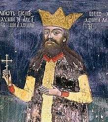 A bearded middle-aged man wearing a crown and holding a cross in his right hand