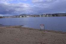 A metal sign erected on the sandy shores of the lake advises of the ban on water activity due to pollution