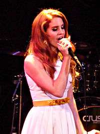 Lana Del Rey is holding a mic in her hand and performing live