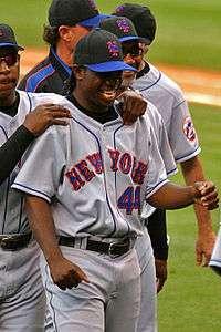 A man in a grey baseball uniform with "New York" and "44" on the chest smiles, surrounded by several men in similar uniforms.
