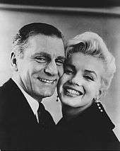 Close-up of smiling Monroe and Laurence Olivier, cheek-to-cheek. She is wearing long diamond earrings.