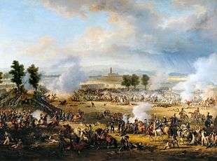  A crowded scene with many soldiers and horses, and much smoke. Some soldiers lie dead or wounded. In the distance, beyond a short line of trees, is a tall church tower.