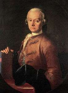  Serios-faced middle-aged man, seated facing half- left, wearing a wig and a heavy brown formal coat
