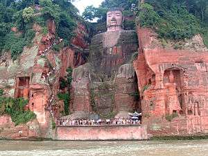 A giant seated buddha cut from a rock face.