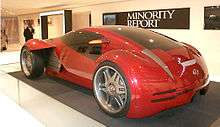 Futuristic two-door concept car displayed in front of a banner labeled "Minority Report".