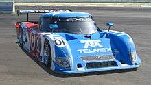 Forward angle view of a racecar on a track; the car is labeled '01', 'Lexus', and 'Telmex'.