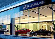 Car showroom with a coupe, two sedans, glass windows, plus large sign reading "Lexus".