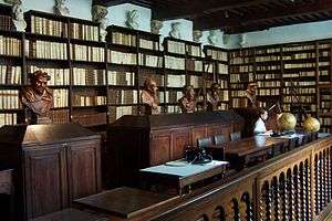 Library with dark wood bookcases and scattered stone busts.