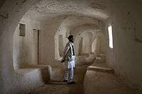 A picture of a man standing in the middle of a hallway made of limestone.