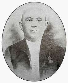 A black and white photograph of a bald Chinese man looking forward