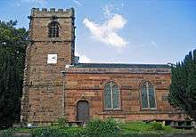 A sandstone church seen from the south; on the left is a crenellated tower with a square clock face; to the right is the body of the church with a doorway and two windows, all round-headed