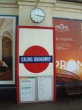A red framed panel contains a red disc with a slightly wider dark blue band across the centre with the words "EALING BROADWAY".