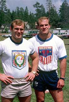 A pair of blonde haired male twins, wearing T-shirts and shorts emblazoned with the USA Olympic team logos.