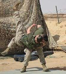 color photo of a Marine tossing another Marine over his shoulder onto a mat.