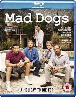 A BD cover with the title "Mad Dogs" at the top. Underneath are five middle aged males, four are sitting while the fifth in the middle is standing and on the telephone. Behind them is a villa.