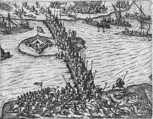 Horsemen fight against each other on a bridge and along a river while ships deliver soldiers on the river