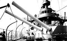 two large rifled cannon pointing out of a turret, aimed over the side of the ship