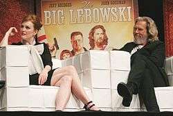 Julianne Moore and Jeff Bridges sitting down in front of a poster of The Big Lebowski