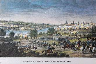 Color-tinted print showing lines of soldiers marching in very straight lines. In the middle distance is a river and on the right horizon is a city.