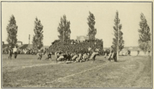 Men lined up in dark sweaters preparing for the beginning of a football play