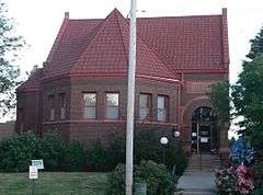 Brick building with steeply-pitched tile roof, arched entrance