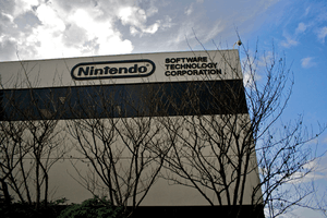 A gray, nondescript building with "Nintendo" written on the top floor, and with trees in the foreground.